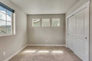 Unfurnished bedroom with light colored carpet, a closet, and a textured ceiling