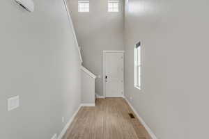 Interior space with a towering ceiling, a healthy amount of sunlight, and light wood-type flooring