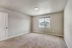 Carpeted spare room featuring a textured ceiling