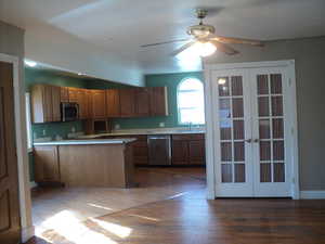 Kitchen with dark hardwood / wood-style flooring, ceiling fan, french doors, and appliances with stainless steel finishes