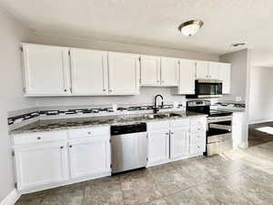 Granite counter tops.  White cabinets.  Long counter top.  Stainless steel appliances.