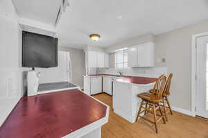 Kitchen featuring sink, light hardwood / wood-style flooring, white appliances, and white cabinets