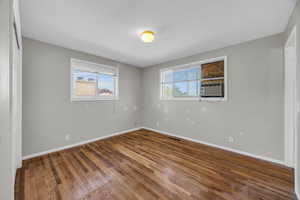 Empty room with hardwood / wood-style floors and cooling unit