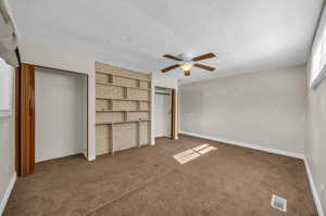 Unfurnished bedroom featuring ceiling fan, a textured ceiling, and carpet flooring