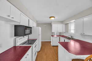 Kitchen featuring sink, light hardwood / wood-style flooring, white appliances, tasteful backsplash, and white cabinetry