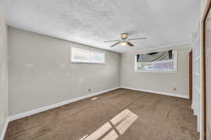 Carpeted spare room featuring ceiling fan and a textured ceiling