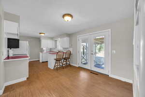 Kitchen with a kitchen breakfast bar, french doors, light hardwood / wood-style floors, kitchen peninsula, and white cabinets