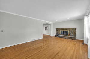 Unfurnished living room featuring light hardwood / wood-style flooring, ornamental molding, and a fireplace