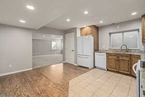 Kitchen featuring sink, light carpet, light stone countertops, and white appliances