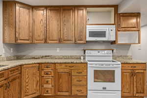 Kitchen featuring light stone countertops and white appliances