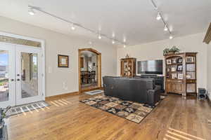 Living room with rail lighting, french doors, and hardwood / wood-style floors