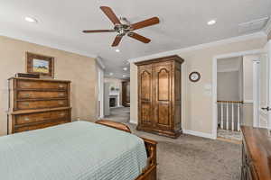 Bedroom featuring light colored carpet, crown molding, and ceiling fan