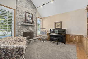 Office area with a stone fireplace, high vaulted ceiling, rail lighting, and light wood-type flooring