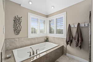 Bathroom with a relaxing tiled tub, plenty of natural light, and tile patterned floors