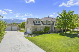 View of front of property featuring a mountain view, a front yard, and a garage