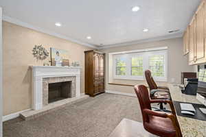 Carpeted home office with crown molding and a brick fireplace