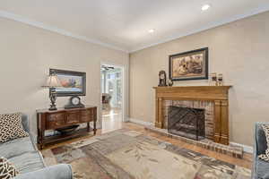 Living room with a fireplace, ornamental molding, and wood-type flooring