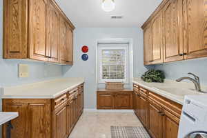 Kitchen featuring sink, washer / clothes dryer, and light tile patterned flooring