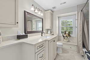 Full bathroom with tile patterned flooring, shower / tub combo with curtain, toilet, and vanity