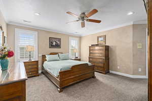 Bedroom featuring ceiling fan, ornamental molding, and light colored carpet