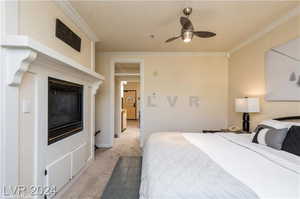 Carpeted bedroom featuring ceiling fan and crown molding