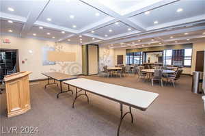 Interior space with coffered ceiling, carpet floors, and beam ceiling