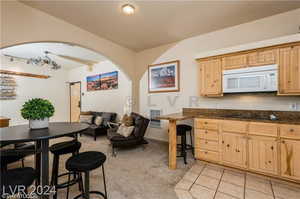 Kitchen with dark stone counters, light brown cabinetry, and light tile patterned flooring