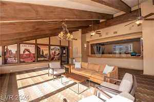 Living room featuring baseboard heating, ceiling fan with notable chandelier, and lofted ceiling with beams