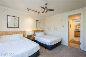 Tiled bedroom featuring ceiling fan, ornamental molding, and track lighting