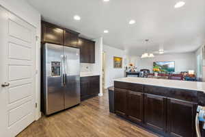 Kitchen featuring decorative light fixtures, a chandelier, dark hardwood / wood-style floors, dark brown cabinetry, and stainless steel fridge with ice dispenser