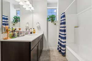 Bathroom with shower / bath combo, a wealth of natural light, tile patterned floors, and vanity