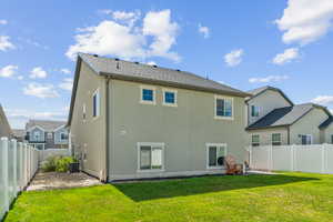 Rear view of house with central AC and a lawn