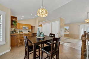 Dining space featuring a notable chandelier, vaulted ceiling, and light tile patterned floors