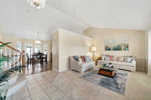 Living room with a notable chandelier, light tile patterned flooring, and lofted ceiling