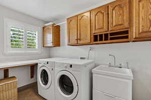 Laundry area featuring dark tile patterned floors, washing machine and clothes dryer, and cabinets