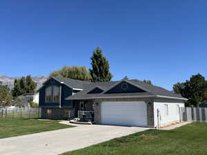 View of front facade featuring a garage, a mountain view, and a front lawn