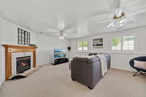 Living room with ceiling fan, a tile fireplace, and light colored carpet