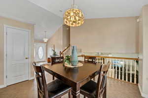 Tiled dining space with a notable chandelier and vaulted ceiling