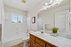 Full bathroom featuring tiled shower / bath combo, tile patterned floors, toilet, and vanity