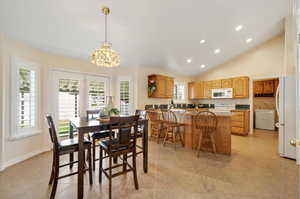 Tiled dining room featuring high vaulted ceiling and a notable chandelier