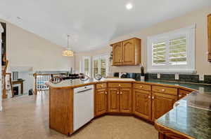 Kitchen featuring sink, pendant lighting, light tile patterned floors, white dishwasher, and kitchen peninsula