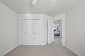 Unfurnished bedroom with ceiling fan, carpet, and a closet