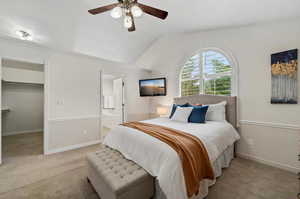 Bedroom with ceiling fan, light carpet, vaulted ceiling, and ensuite bathroom