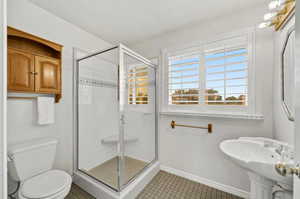 Bathroom with sink, tile patterned flooring, an enclosed shower, and toilet