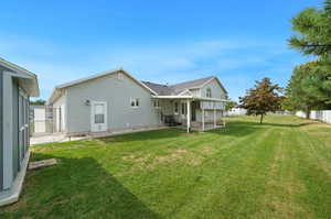 Rear view of property featuring a lawn and a patio area