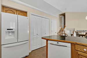 Kitchen featuring white appliances, lofted ceiling, and light tile patterned flooring