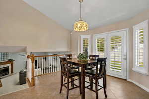 Tiled dining room featuring a wealth of natural light, vaulted ceiling, and a tile fireplace