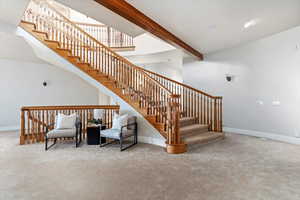 Staircase featuring beam ceiling and carpet