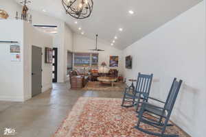 Sitting room with ceiling fan with notable chandelier and high vaulted ceiling