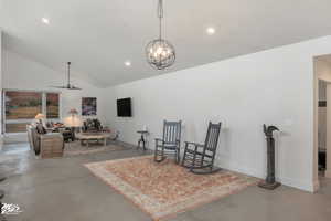 Interior space with ceiling fan with notable chandelier, vaulted ceiling, and concrete floors